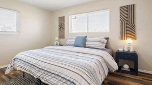 Ein Schlafzimmer mit Bett, Nachttischen und Wandbildern.