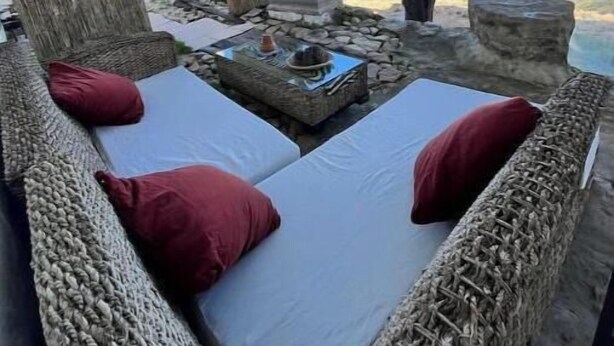 Un espace extérieur aménagé avec des meubles en osier, un hamac et une vue sur le paysage.
