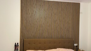 Een slaapkamer met een bed, hoofdeinde, nachtkastje en een wandpaneel.