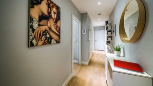 A hallway with a painting, a mirror, and a red book on a white console. - Stylish Flat by Victoria Park (London)