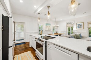 A modern kitchen with white cabinetry, a central island, a built-in oven, and pendant lighting. - Home with Community Pool, Screened-in Porch, Bikes and Grill (Seacrest Beach)
