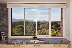 Eine Küche mit großem Fenster, Granitarbeitsplatte und Blick auf eine Berglandschaft.