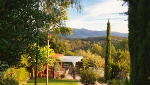 Un chemin de pierres mène à une maison dotée d’un jardin et offrant une vue sur des collines lointaines.