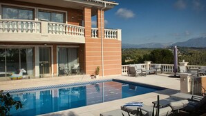 Une maison à deux étages avec une piscine, un espace salon extérieur et une vue sur les montagnes.