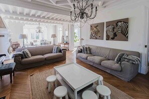 A spacious living room with two sofas, a piano, and a chandelier. - Exceptional historic house with swimming pool (Yerres)