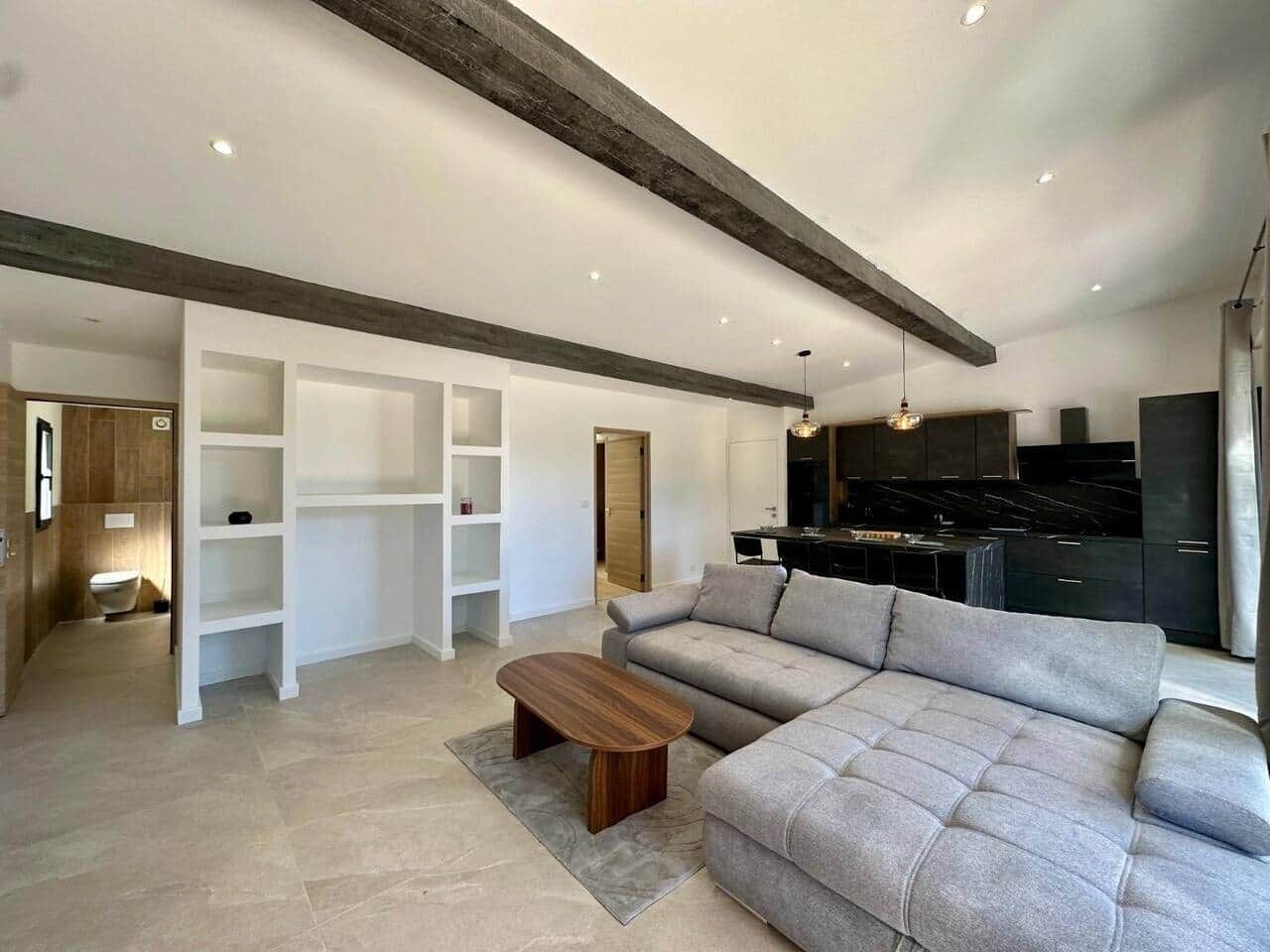 A modern living room with a grey sofa, wooden coffee table, and built-in white shelving.