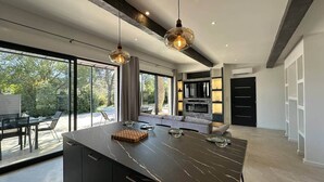A modern kitchen with a large island, pendant lighting, and a view of the outdoors.