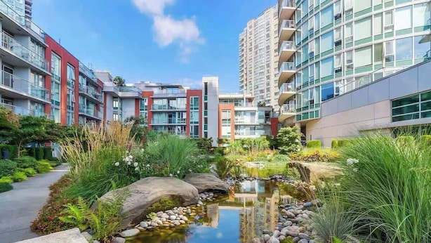 Un immeuble d’appartements moderne avec un petit étang et de la verdure environnante.