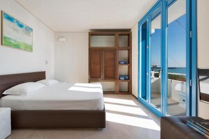 A bedroom with a bed, a wardrobe, a sofa, and a balcony with a view.
