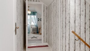 Un passadís amb una catifes de dibuixos de les estrelles, un radiador i una porta de fusta.