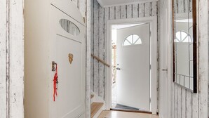 Un passadís amb una porta blanca, un marc de porta de fusta, un mirall i una cinta vermella a la porta.