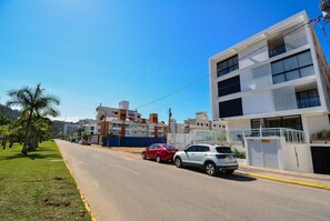A street with parked cars, buildings, and a clear sky. - Charme e Conforto - 400m Praia de Palmas (Governador Celso Ramos)