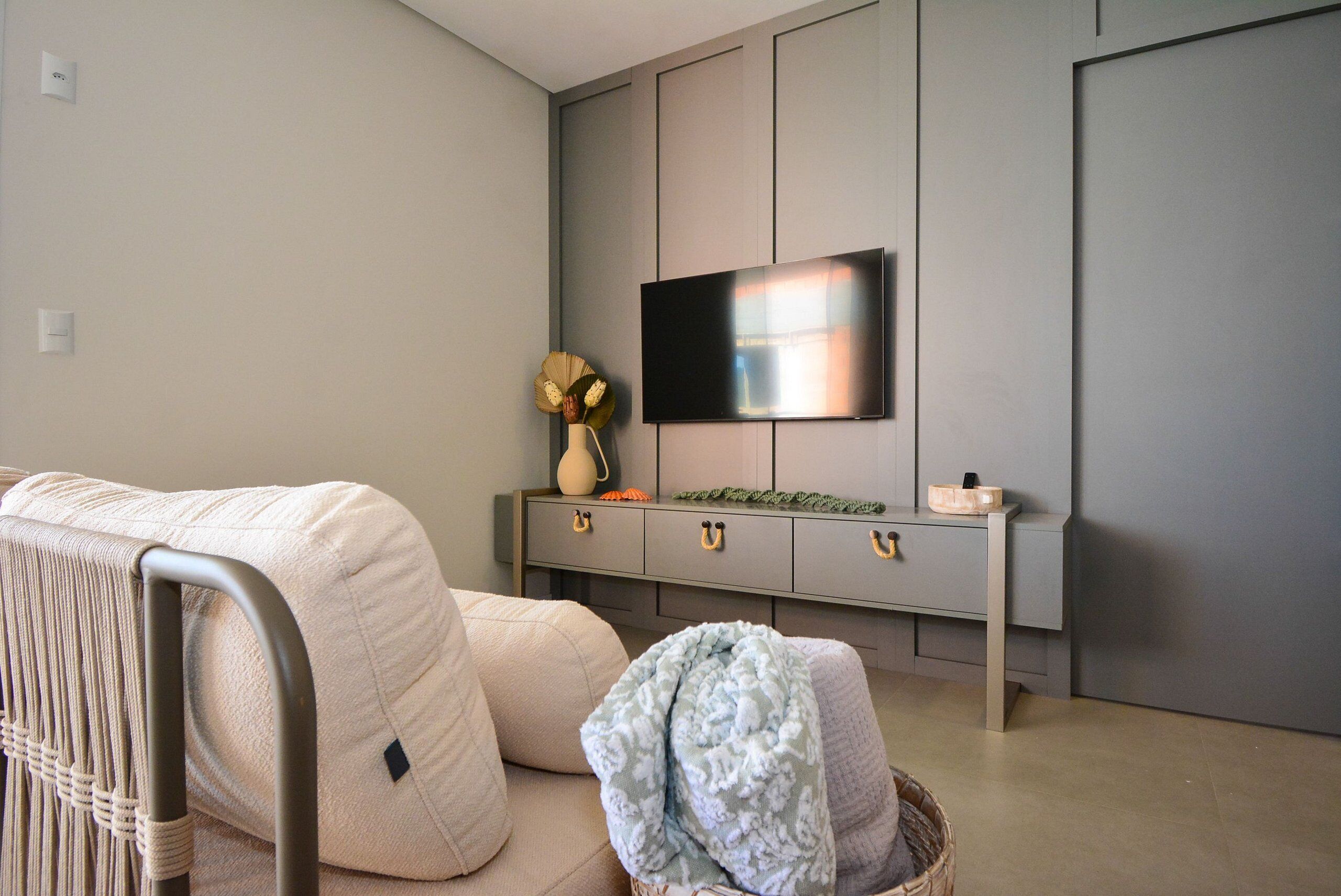A modern living room with a sofa, a television mounted on the wall, a console table with decorative items, and a basket on the floor.