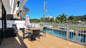 A balcony with a pool, outdoor furniture, and a view of the surrounding area. - Charme e Conforto - 400m Praia de Palmas (Governador Celso Ramos)