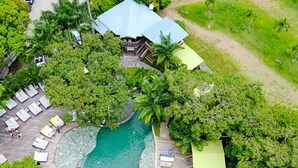 An aerial view of a resort with a swimming pool, lounge chairs, and lush greenery.