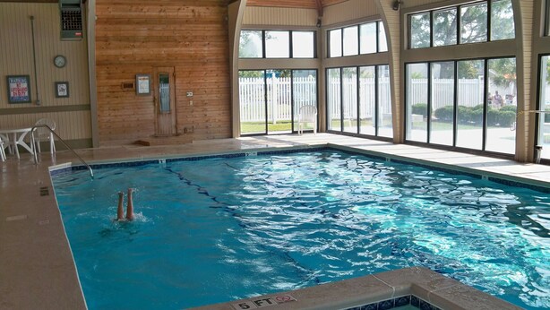 An indoor swimming pool with clear water, wooden walls, and large windows. - Luxury Condo with Golf Course Views, Pools & Resort Access! (New Bern)