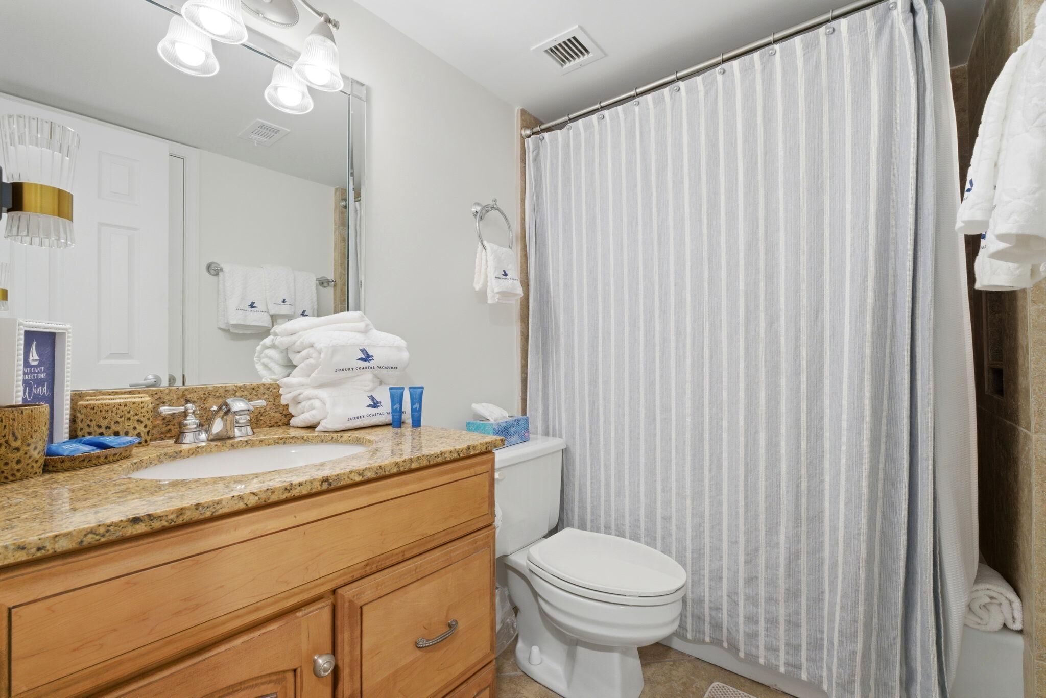 A bathroom with two sinks, a toilet, a shower curtain, and a mirror.