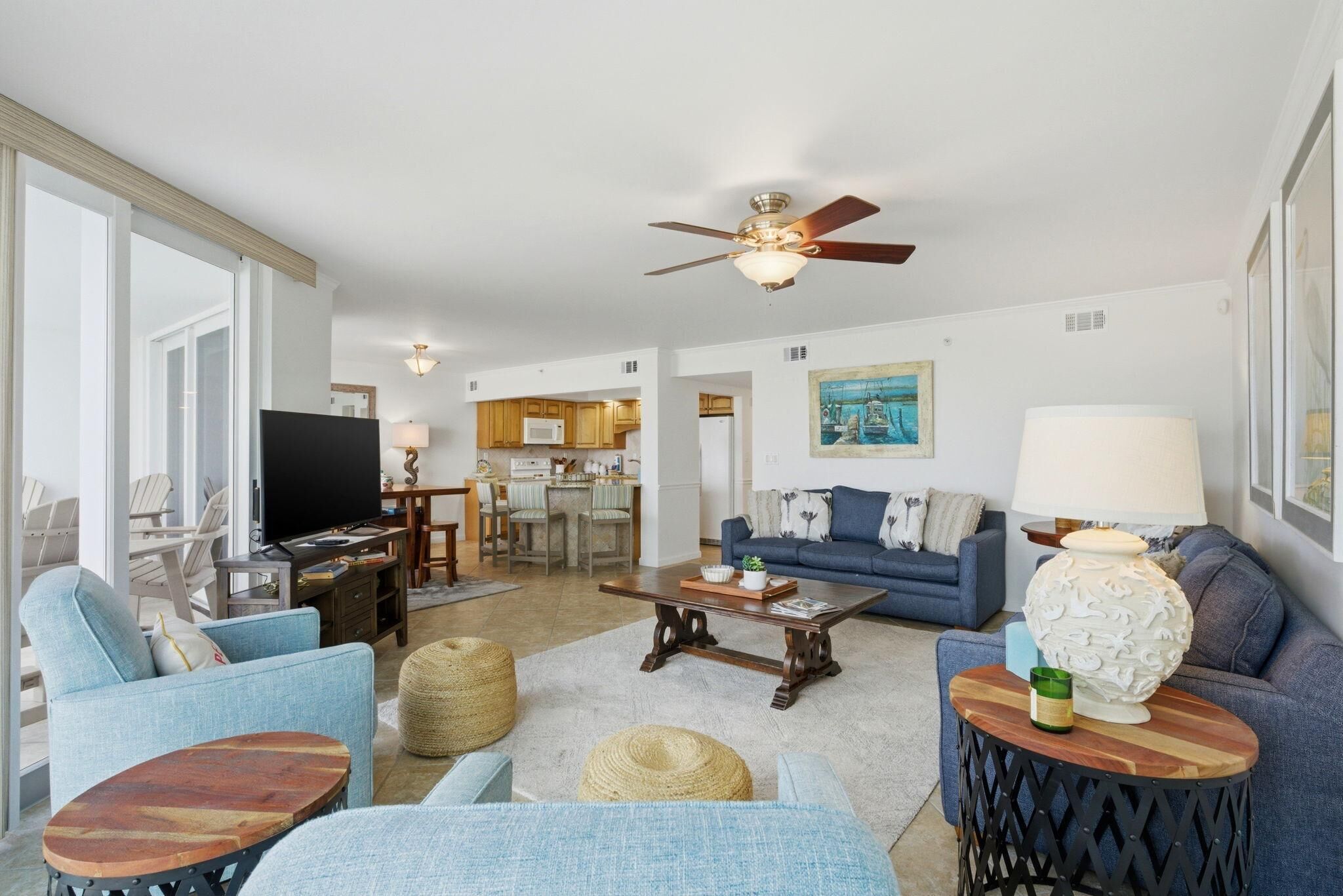 A living room with a television, sofas, a coffee table, and a ceiling fan.