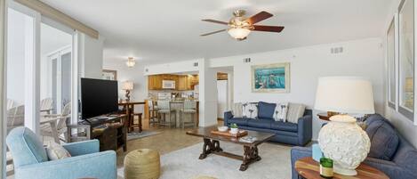 A living room with a television, sofas, a coffee table, and a ceiling fan.