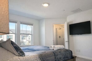 Ein Schlafzimmer mit Bett, Fernseher, Dusche und Blick ins Freie.
