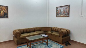 Ein Wohnzimmer mit einer Couch, einem Couchtisch, einem gemusterten Teppich und zwei gerahmten Bildern an den Wänden.