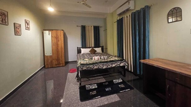 Ein Schlafzimmer mit einem Bett, einem Holzschrank, einem Schreibtisch und einem Deckenventilator.