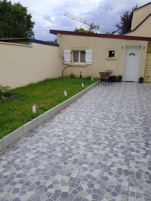 A courtyard with a tiled floor, a small table with chairs, and a door.