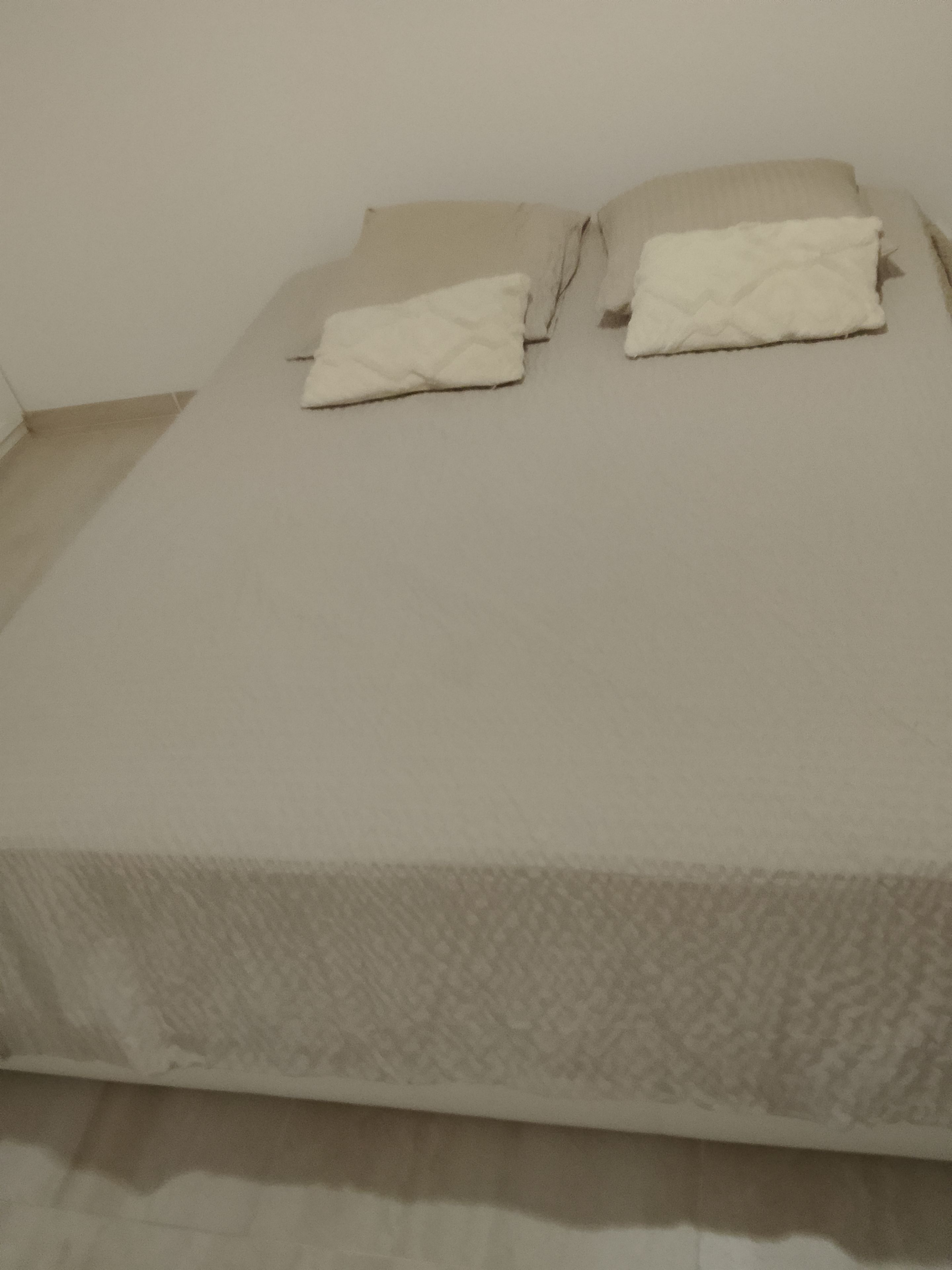 A bed with a textured bedspread and two pillows.