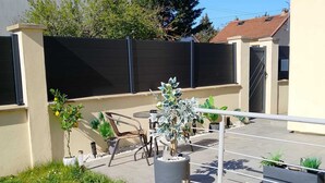 Un quartier résidentiel doté d’une terrasse dallée, de meubles de jardin et de plantes en pot.