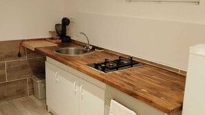 Une cuisine avec un plan de travail en bois, un évier, une cuisinière et des armoires blanches.