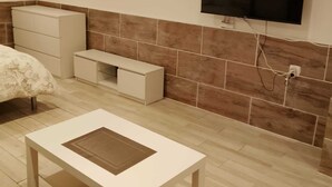 Une chambre moderne équipée d’un lit, d’un téléviseur fixé au mur, d’une petite table et d’un meuble.