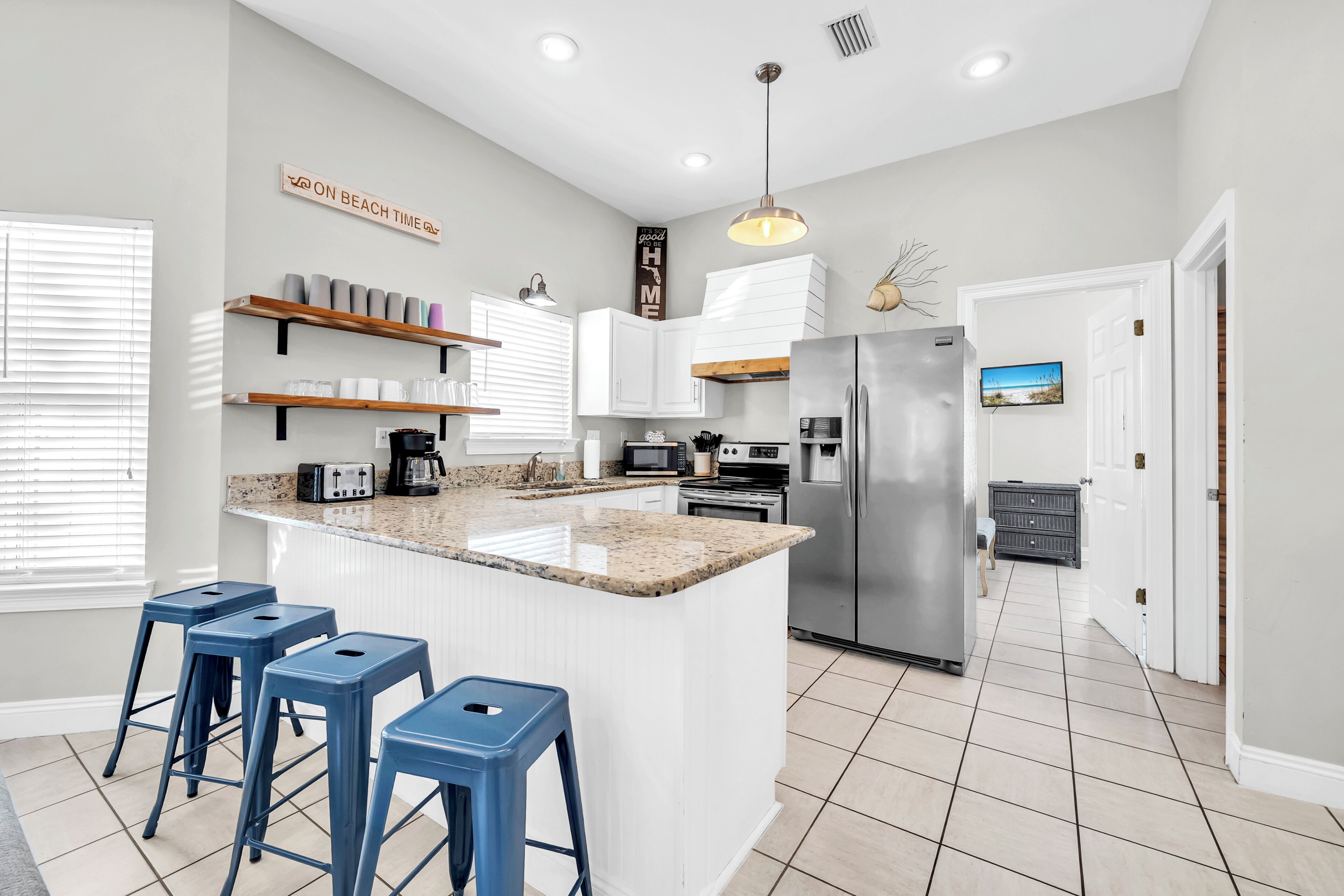 A modern kitchen with a central island, bar stools, built-in appliances, and a view of the living area.