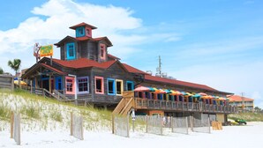 Un edificio in legno colorato con tetto rosso, un balcone con ombrelloni e un cartello con su scritto "Dunraven Joe's".