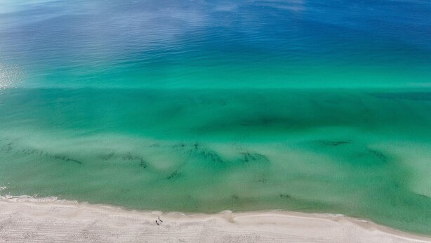 Una spiaggia con acque turchesi trasparenti e una battigia sabbiosa.