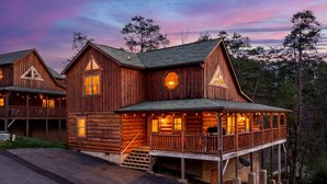 A wooden cabin with a porch, large windows, and a deck. - Indoor Pool + Arcade Loft | 4 En-Suite BRs | Gated Bear Crossing Cabin (Sevierville)