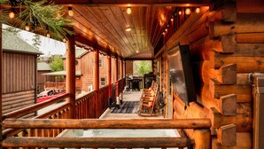 A wooden log cabin with a covered porch, outdoor seating, and a grill area. - Indoor Pool + Arcade Loft | 4 En-Suite BRs | Gated Bear Crossing Cabin (Sevierville)