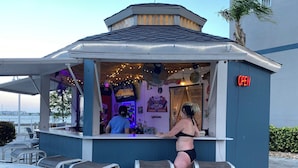 Een klein openluchtcafé met een bar, stoelen en uitzicht op het water.