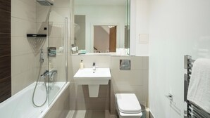 Un baño moderno con ducha de vidrio, lavamanos blanco y retrete.