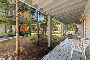 A covered outdoor area with wooden decking, a bench, and a view of a building with a wooden facade. - NEW! Pine Creek Townhome, Private Hot Tub & Garage (Breckenridge)