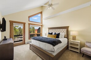 Ein Schlafzimmer mit einem großen Bett, einem Deckenventilator, einem Nachttisch, einem Sessel und einem Fernseher.
