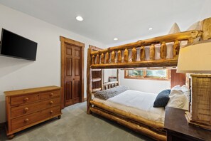 Ein Zimmer mit einem Etagenbett, einem Holzschrank und einem an der Wand befestigten Fernseher.