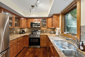 A modern kitchen with wooden cabinets, stainless steel appliances, a built-in oven, and a large window. - NEW! Pine Creek Townhome, Private Hot Tub & Garage (Breckenridge)
