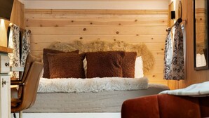 Ein gemütliches Zimmer mit einem Bett, Holzwänden, einem Sessel und einem kleinen Tisch.