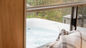 Blick aus dem Fenster auf ein Whirlbad mit Holzrahmen und einer karierten Decke.