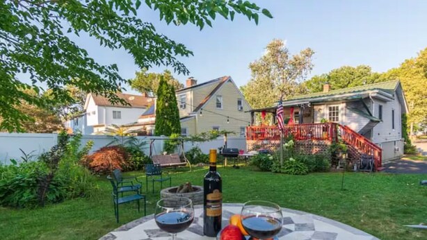 A patio with a table set for two, a bottle of wine, and a fruit bowl.