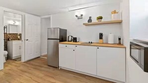 A compact kitchen with white cabinetry, a stainless steel refrigerator, a wooden countertop, and a built-in oven.