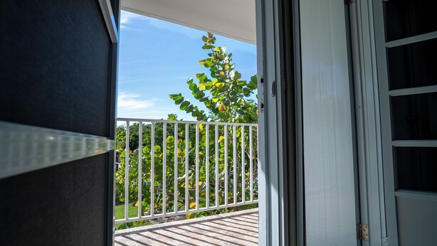 Een balkon met uitzicht op een tuin en een witte hek.