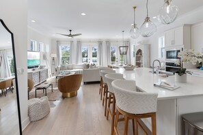 Una cucina moderna con mobili bianchi, un'isola centrale e illuminazione a sospensione.