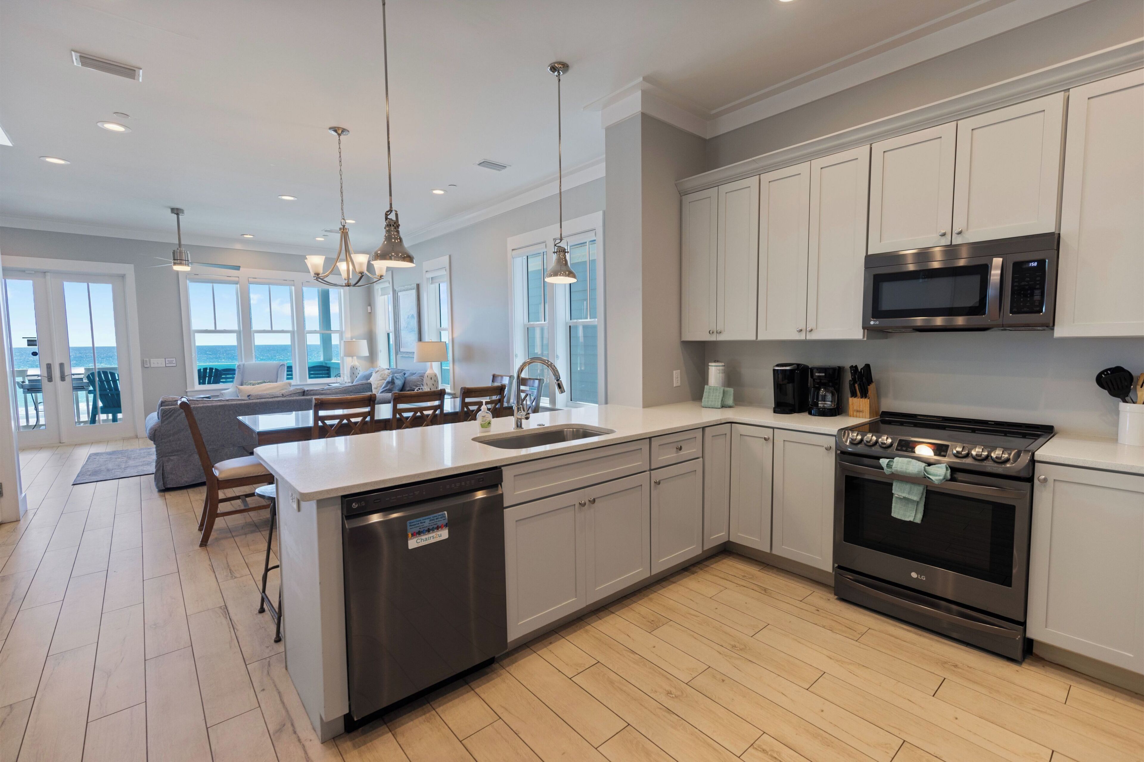 A modern kitchen with a central island, stainless steel appliances, and a view to the outside.