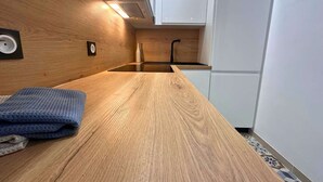 A compact kitchen with a wooden countertop, a sink, and white cabinetry. - Asteria by Pom, pkg, clim, wifi (Agde)